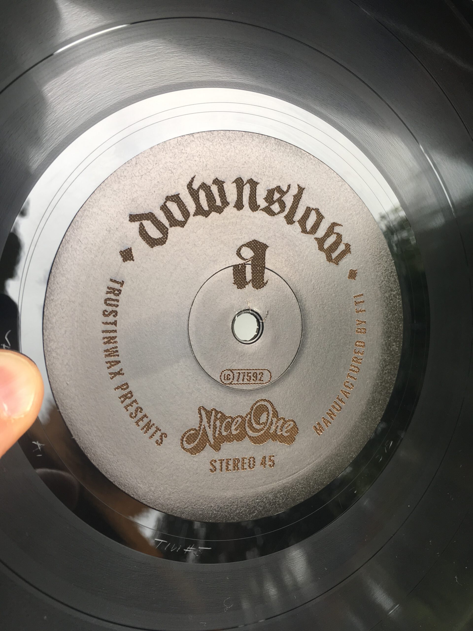 Nahaufnahme des beidseitig gelaserten Schallplattenetiketts der limitierten 10″-EP „Doom, Dub + Dosenbier“ von Downslow mit gebrochener Typografie und Trust-in-Wax-Logo.